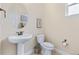 Small bathroom with a pedestal sink and toilet, decorated with a round mirror and neutral wall art at 49 Willowcroft Dr, Littleton, CO 80123