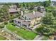 Expansive aerial view of a yellow two-story home with a porch, set among lush greenery and other residences at 9385 Prairie View Dr, Highlands Ranch, CO 80126