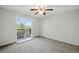 This carpeted bedroom has sliding glass doors to a private balcony with tree views and a ceiling fan at 17593 E Temple Dr, Aurora, CO 80015