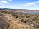 Breathtaking aerial view of a landscape featuring houses nestled amongst trees, a lake, and rolling hills under a blue sky at 14475 Foothill Rd, Golden, CO 80401