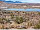 Scenic aerial view featuring a serene lake surrounded by lush trees and houses, with majestic mountains in the horizon at 14475 Foothill Rd, Golden, CO 80401