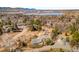 Aerial view of a neighborhood with houses nestled amongst mature trees, near a lake and mountains in the distance at 14475 Foothill Rd, Golden, CO 80401