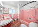 Vintage-style pink tiled bathroom featuring a matching pink sink and bathtub, and modern lighting fixtures at 14475 Foothill Rd, Golden, CO 80401