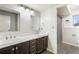 Bathroom with double sinks, dark wood cabinets, large mirror, and an adjacent shower at 1285 Spinnaker Trl, Monument, CO 80132