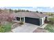 Charming home exterior featuring a dark garage door, gray roof, and well-maintained landscaping at 1285 Spinnaker Trl, Monument, CO 80132