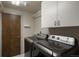 Laundry room with modern front-loading washer and dryer, white cabinets, and a wooden door at 180 N Cook St # 509, Denver, CO 80206