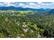 Stunning view of a home surrounded by lush forest with mountain views and meadows at 7284 Willa Ln, Evergreen, CO 80439