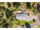 Aerial view showcases home with grey roof, deck, and gravel driveway nestled among trees at 7284 Willa Ln, Evergreen, CO 80439