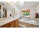 Relaxing bathroom featuring a soaking tub, vanity and window providing natural light at 7284 Willa Ln, Evergreen, CO 80439