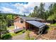 Charming home with wood siding, covered parking area, and an attached garage nestled amongst mature trees at 7284 Willa Ln, Evergreen, CO 80439