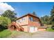 Charming two-story home with a wooden deck and two-car garage nestled amongst mature trees under a bright blue sky at 7284 Willa Ln, Evergreen, CO 80439