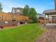 Landscaped backyard featuring a lush lawn, retaining wall flower beds, and mature trees at 3838 Brush Rd, Castle Rock, CO 80108