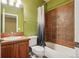 Cozy bathroom featuring a shower-tub combo with tiled walls, vanity, toilet, and olive green painted walls at 13075 Tamarac St, Thornton, CO 80602