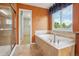 Relaxing bathroom with a garden tub, shower with glass enclosure, and a large window at 13075 Tamarac St, Thornton, CO 80602