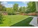 Large backyard with mature trees, wood fence, and green grass at 6155 Carr St, Arvada, CO 80004