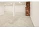 Spacious basement area with white walls, neutral carpet, and a decorative brick element at 6155 Carr St, Arvada, CO 80004