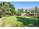 Expansive backyard featuring green lawn, mature trees, and an elevated wooden deck at 1010 Home Farm Cir, Denver, CO 80234
