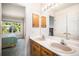 Bright bathroom boasts double sinks, wood cabinetry, neutral countertops, and a view into an adjacent bedroom at 1010 Home Farm Cir, Denver, CO 80234