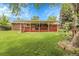 Brick home and covered patio with lush lawn and manicured landscaping in backyard at 1160 Johnson St, Lakewood, CO 80215