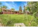 Expansive backyard featuring a windmill, brick home, covered patio, lush lawn, and well-manicured landscaping at 1160 Johnson St, Lakewood, CO 80215