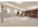 Basement area with exposed support beams, a brick fireplace, and a custom-built wooden bar with storage shelves at 1160 Johnson St, Lakewood, CO 80215