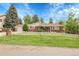 Charming red brick home featuring a well-manicured lawn, white picket fence and mature trees at 1160 Johnson St, Lakewood, CO 80215