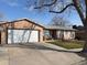 Single-story home features a large two-car garage and is surrounded by a lush green lawn at 8757 W 75Th Way, Arvada, CO 80005