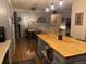 Open kitchen boasts butcher block island, stainless appliances, pendant lighting, and hardwood flooring at 8757 W 75Th Way, Arvada, CO 80005