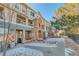 Exterior view of townhomes featuring stone accents and patios with snowy sidewalks at 494 Black Feather Loop # 117, Castle Rock, CO 80104