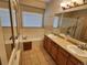 Bathroom featuring dual vanities, a large mirror, and a bathtub and shower combination at 221 Homestead Pkwy, Longmont, CO 80504