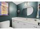 The bathroom features a modern vanity, round mirror and a bold accent wall at 5081 S Emporia St, Greenwood Village, CO 80111