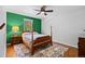 A bedroom featuring green accent wall, ceiling fan, and stylish wooden four-poster bed on hardwood floor at 5081 S Emporia St, Greenwood Village, CO 80111