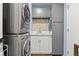 Convenient laundry room features a stacked washer and dryer unit with sink and extra storage at 5081 S Emporia St, Greenwood Village, CO 80111
