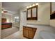 Bathroom with dual sinks, vanity, and access to the main bedroom with large bed and window at 12028 W Aqueduct Dr, Littleton, CO 80127
