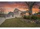 Two-story home with a lush front lawn, two car garage and striking red shutters, all under a beautiful sunset at 12028 W Aqueduct Dr, Littleton, CO 80127
