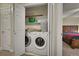 Convenient laundry area with modern washer and dryer units, plus shelving for storage next to the main bedroom at 12028 W Aqueduct Dr, Littleton, CO 80127