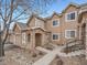 Tan two-story townhome with stone accents, attached garage, and landscaped walkway at 2833 W 119Th Ave # 15-102, Denver, CO 80234