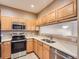 Galley-style kitchen with light wood cabinets and stainless steel appliances at 2833 W 119Th Ave # 15-102, Denver, CO 80234