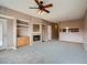 Spacious living room with gray carpet, a fireplace, ceiling fan, and built-in shelving at 2833 W 119Th Ave # 15-102, Denver, CO 80234