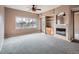 Open living room features a fireplace, shelving, a ceiling fan, and large windows with a scenic view at 2833 W 119Th Ave # 15-102, Denver, CO 80234