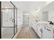 Bright bathroom showcasing double vanity, glass-enclosed shower, and a soaking tub next to a large window at 4066 N Irvington St, Aurora, CO 80019