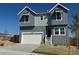 Beautiful two-story home featuring gray siding, white garage door, and charming front entrance under a clear blue sky at 16947 W 92Nd Dr, Arvada, CO 80007
