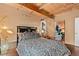 Cozy bedroom featuring wood floors, exposed beam ceiling, and monochrome decor at 6619 Apache Pl, Larkspur, CO 80118