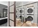 Convenient laundry room with stacked washer and dryer, mirrored wall, and ample storage space at 6619 Apache Pl, Larkspur, CO 80118