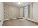 Bedroom featuring a patterned accent wall, carpeted floor, and a window with drapes at 5876 Alton St, Denver, CO 80238