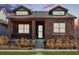Charming brick home with dormer windows and inviting front porch showcasing manicured landscaping at 5876 Alton St, Denver, CO 80238