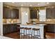 Stylish kitchen with dark wood cabinets, a center island with seating, and modern backsplash at 5876 Alton St, Denver, CO 80238