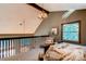Lofted bedroom with a cozy armchair, wood beams, and natural light at 25257 Snyder Ave, Conifer, CO 80433