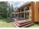 Beautiful home featuring a large wooden deck with ample seating overlooking a well-manicured lawn at 25257 Snyder Ave, Conifer, CO 80433