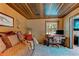 Cozy room featuring a wood plank ceiling, comfortable seating, and a desk with woodland views at 25257 Snyder Ave, Conifer, CO 80433
